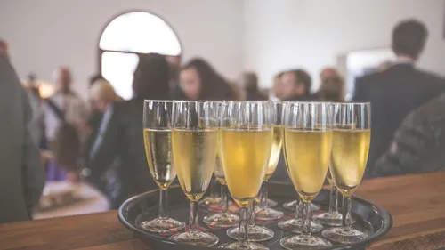 Champagne glasses on tray in crowded room.