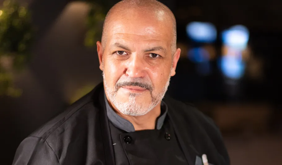 Glatzköpfiger Mann in Kochuniform drinnen.