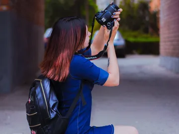 A person takes pictures with a camera in a street.
