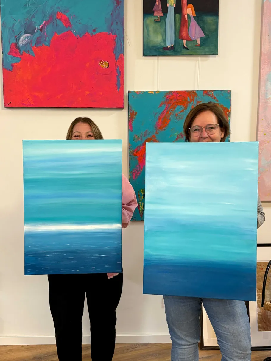 Zwei Personen halten Meerbilder in Kunstgalerie.