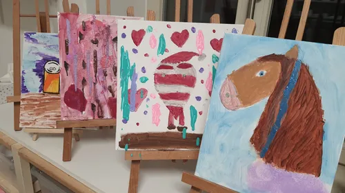 Four colorful paintings displayed on easels.