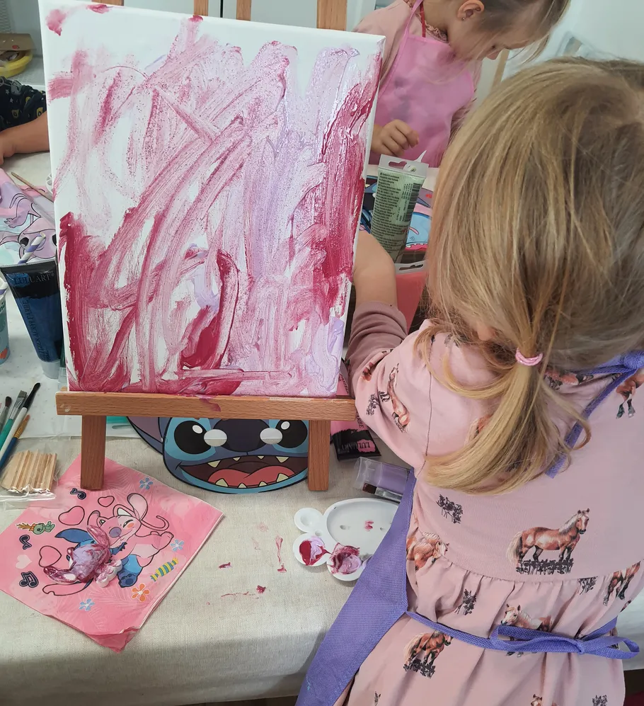 Child painting on canvas with red paint.