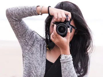 Frau fotografiert mit Kamera am Strand.