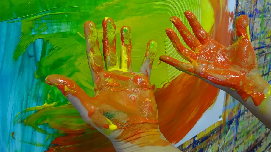 Hände voller Farbe auf bunter Leinwand.
