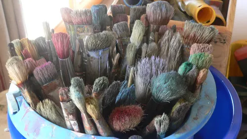 Gebrauchte Pinsel in einem blauen Behälter.