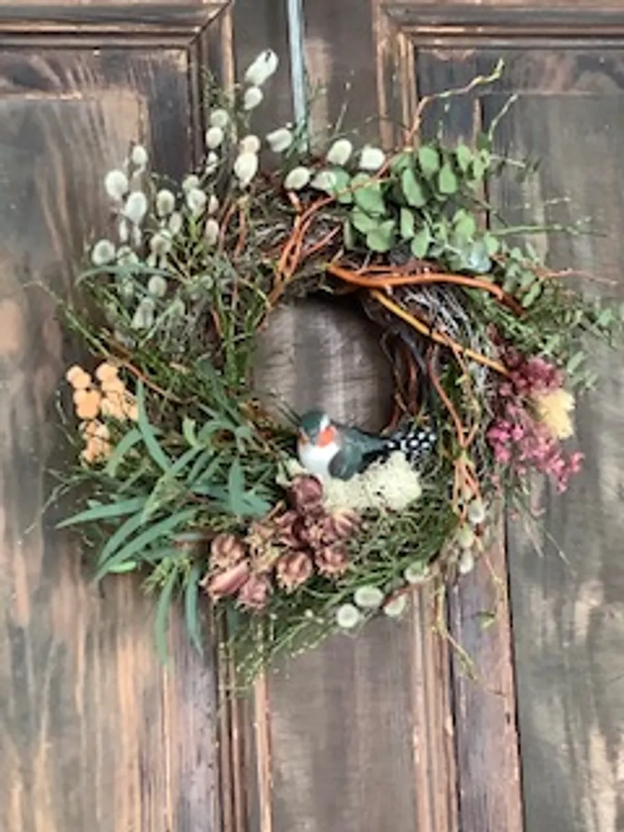 Dekorativer Kranz mit Vogel an Holztür.