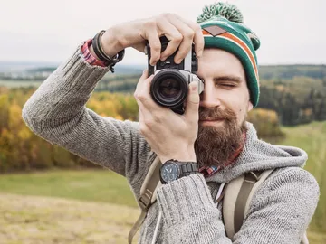 Mann mit Kamera fotografiert in einer natürlichen Landschaft.