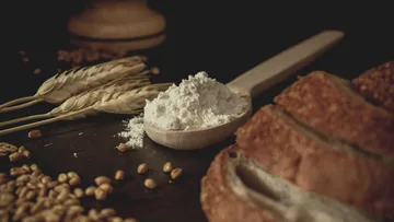 Flour on spoon with wheat and bread.