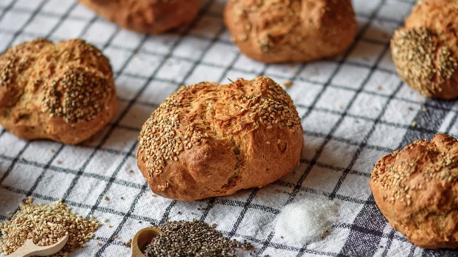 Bread rolls with seeds on checkered cloth.