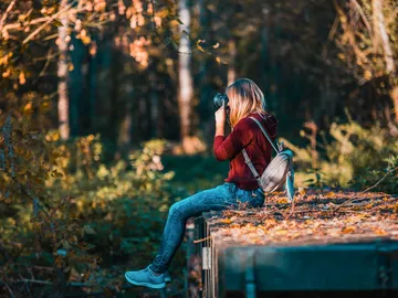 Eine Person fotografiert in einem herbstlichen Wald.
