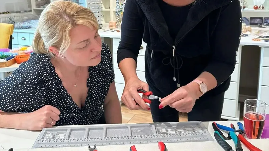 Two women working with jewelry tools in studio.