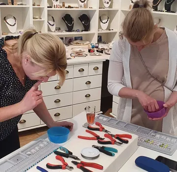 Two women crafting jewelry in a store.
