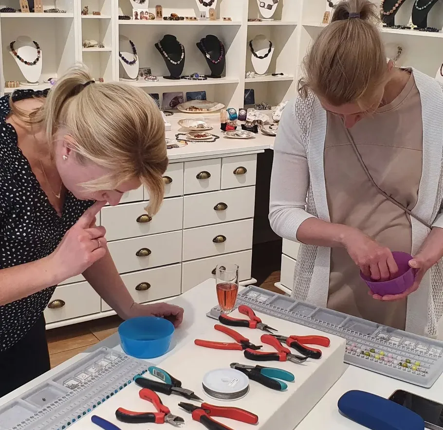 Two women crafting jewelry in a store.