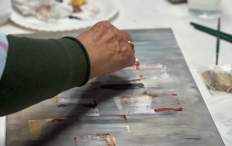 Person painting abstract art on canvas.