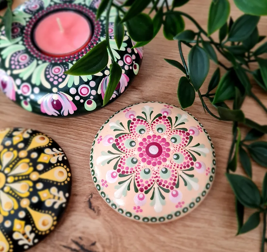 Colorful mandala stones with leaves on wood table.