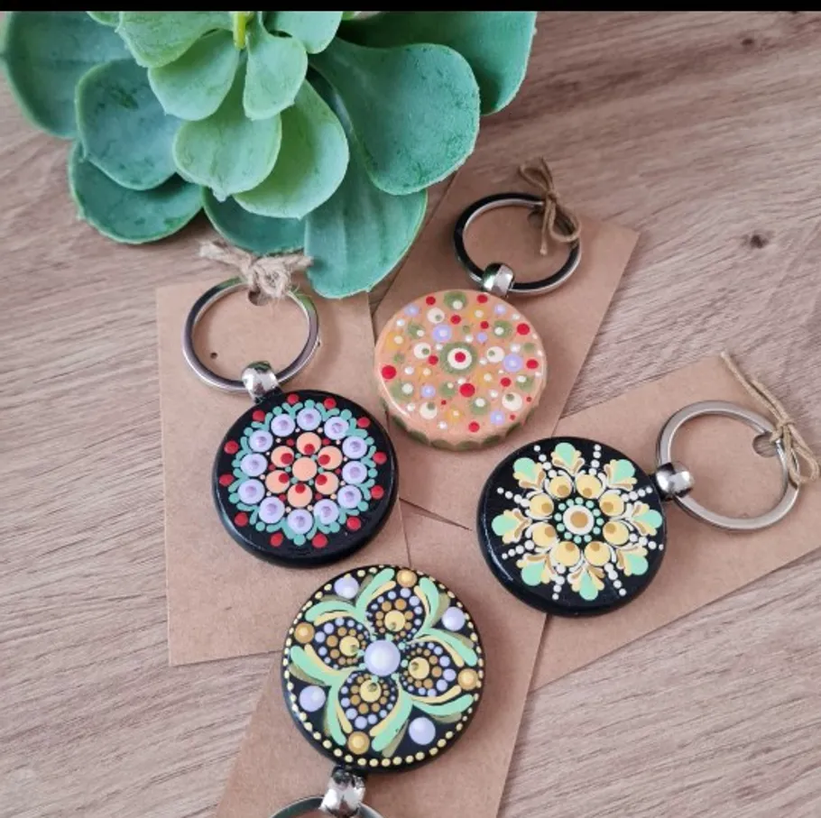 Vier bunte Mandala-Schlüsselanhänger auf Holztisch.