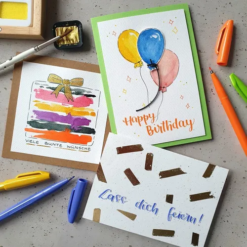 Three colorful greeting cards with art supplies.