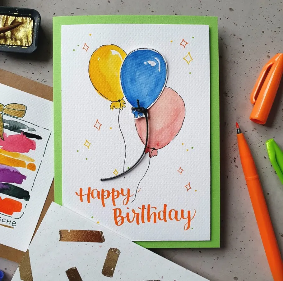 Birthday card with colorful balloons on desk.