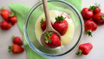 Erdbeeren in Sahne mit Holzlöffel.