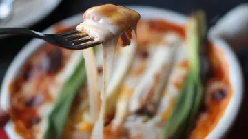 Fork lifting cheesy pasta from bowl.