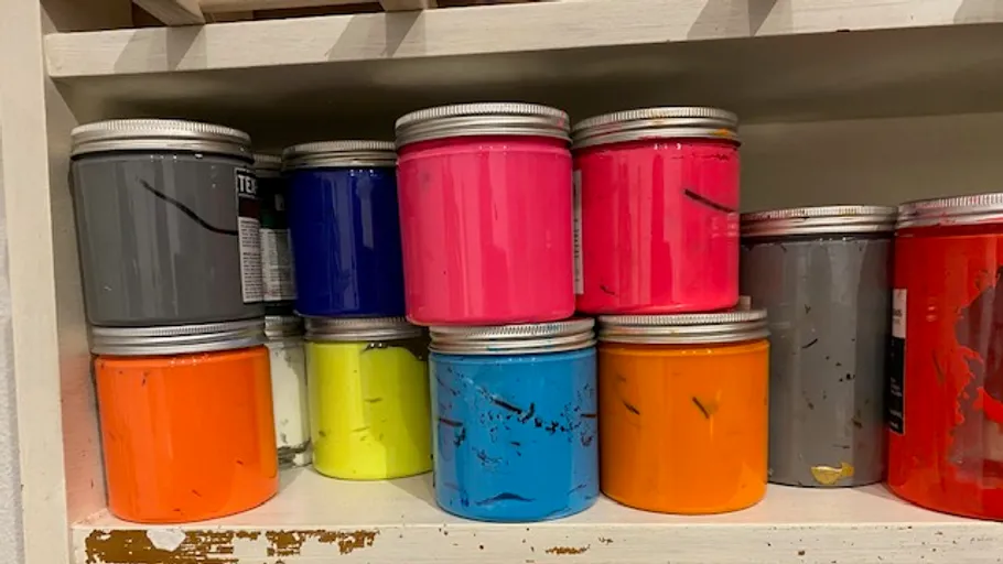 Bunte Farbdosen auf Regalen gestapelt.