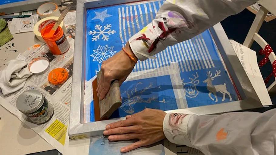 Person screen printing with holiday designs.