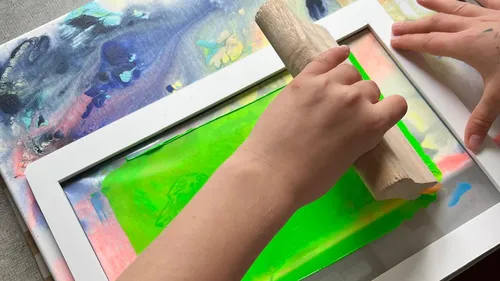 Hände benutzen Rakel zum Siebdrucken.