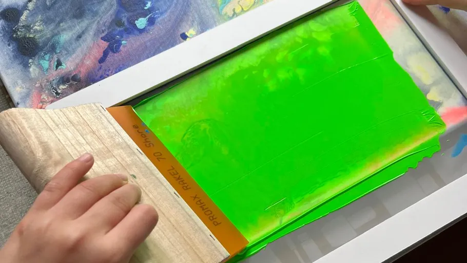 Hand benutzt Rakel mit leuchtender grüner Tinte.