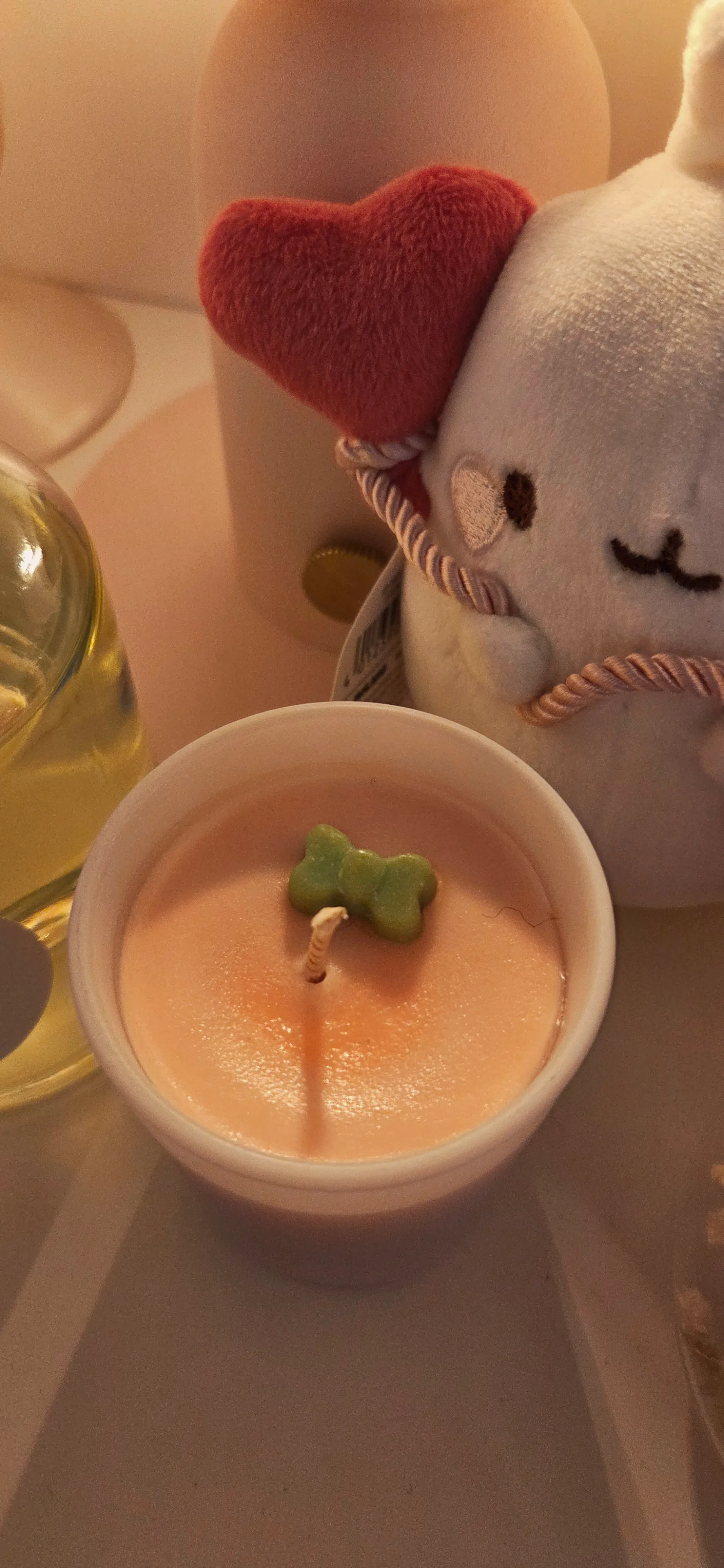 Rosa Kerze und Plüschtier auf Tisch.