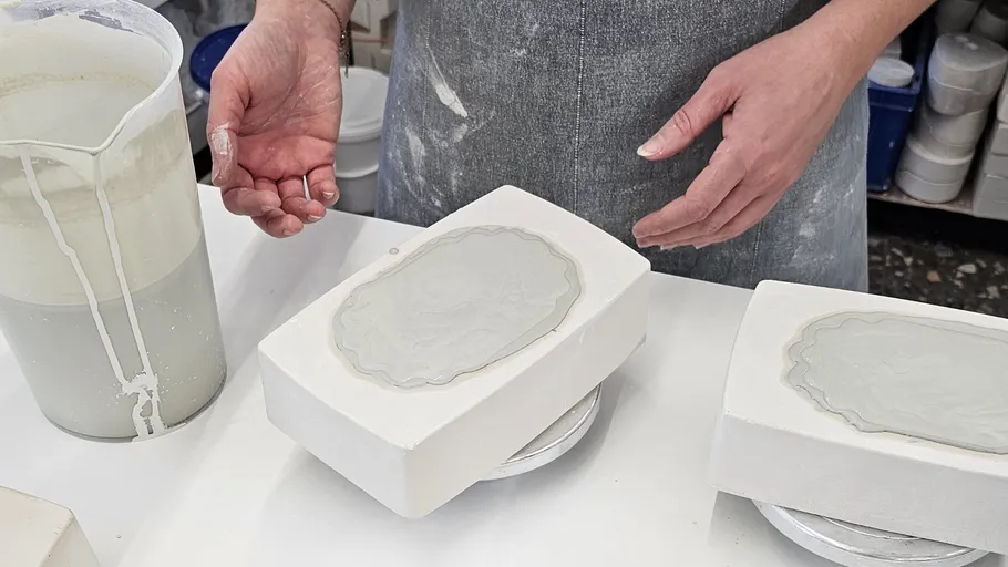 Person shaping clay slab in pottery studio.