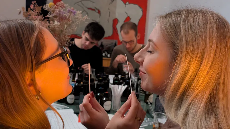 Zwei Frauen riechen Duftstreifen, andere mischen Parfums.