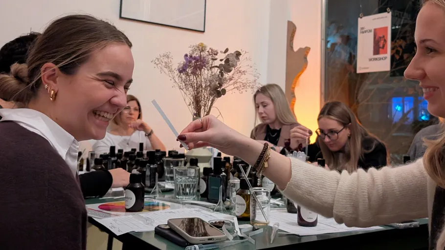 People laughing and testing perfumes in a workshop.