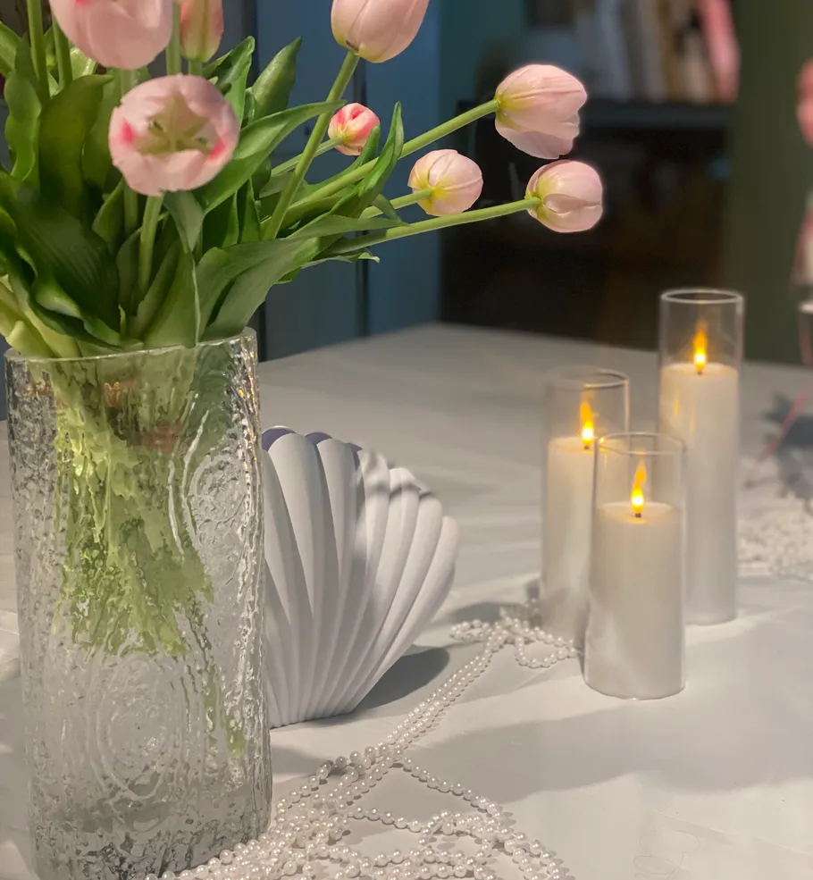 Pink tulips in a vase, candles on table.