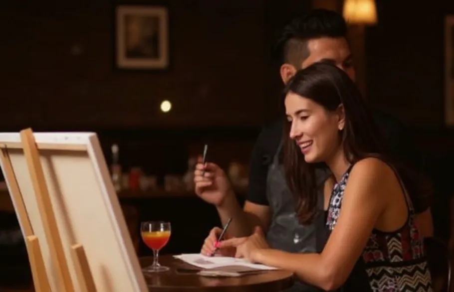 Woman drawing in bar with drink nearby.