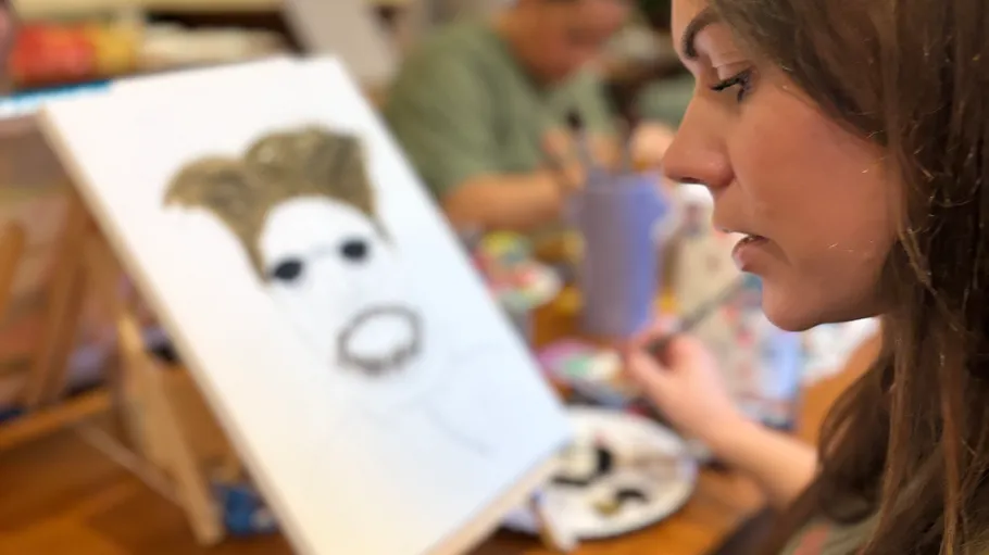 Woman painting on canvas in art class.