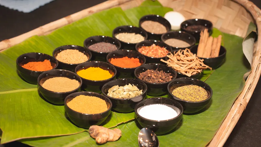 Spices in bowls on a banana leaf.