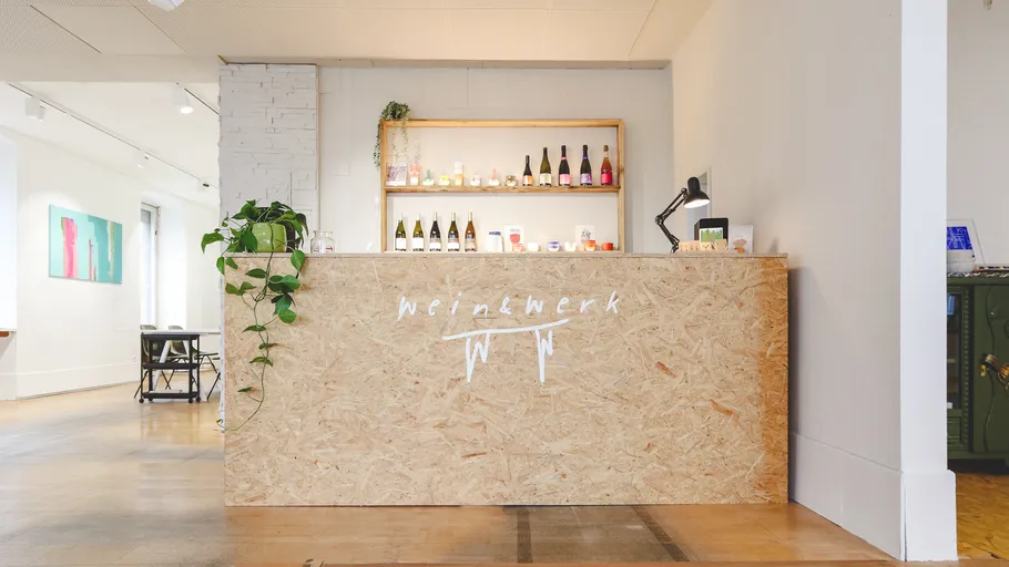 Wooden counter displaying wine bottles in a shop.
