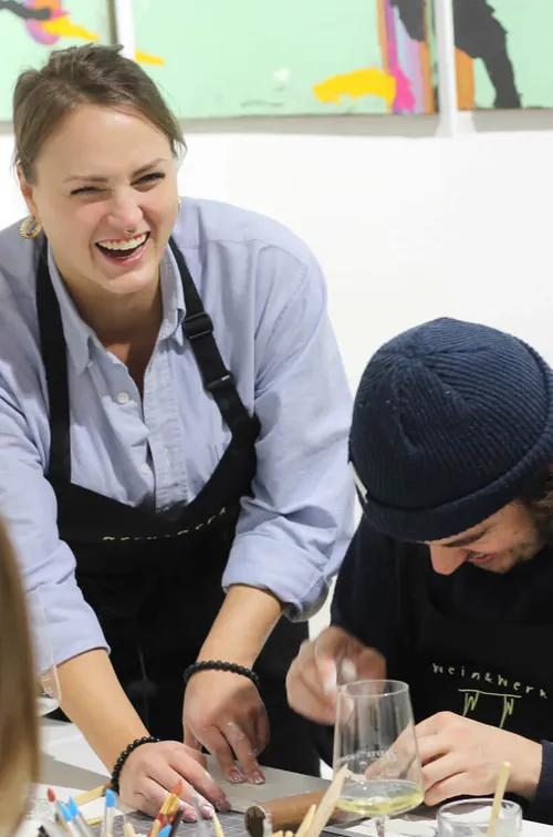 Zwei Personen lachen in einem Kunstkurs.