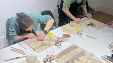 Personen formen Ton an einem Tisch.