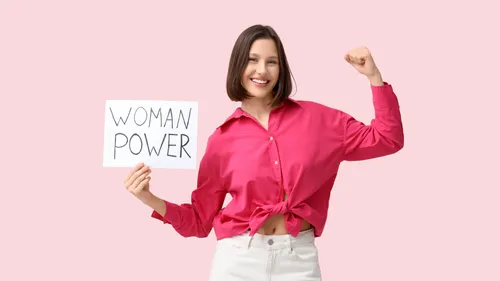 Woman holding sign, showing strength in pink shirt.
