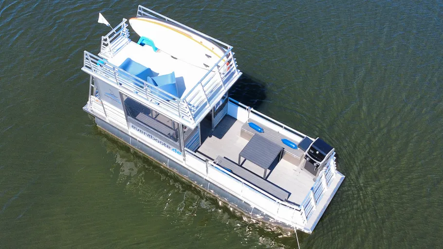 Floating houseboat with upper deck on water.