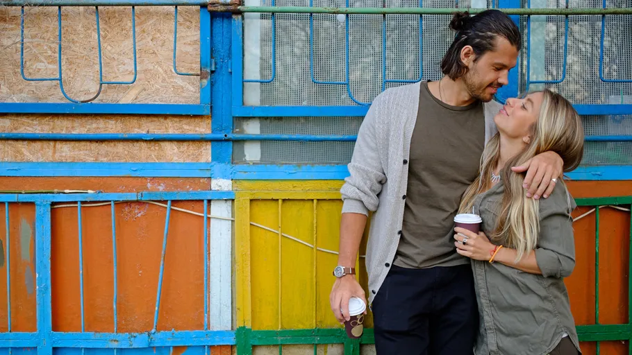 Couple with coffee cups smiling outdoors.
