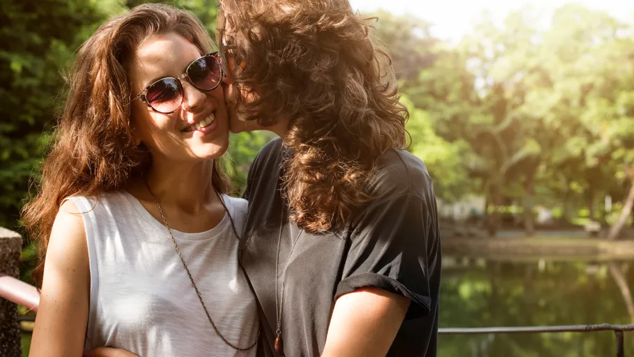 Two people smiling and embracing outdoors.