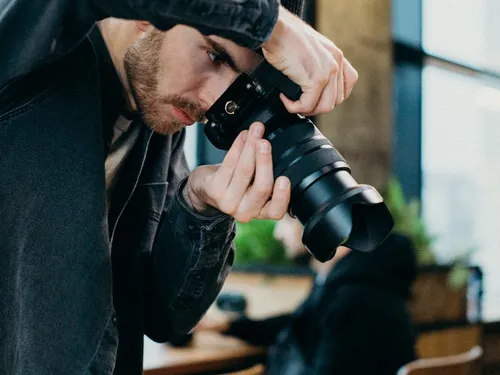 A photographer focuses his camera on a subject in a café.
