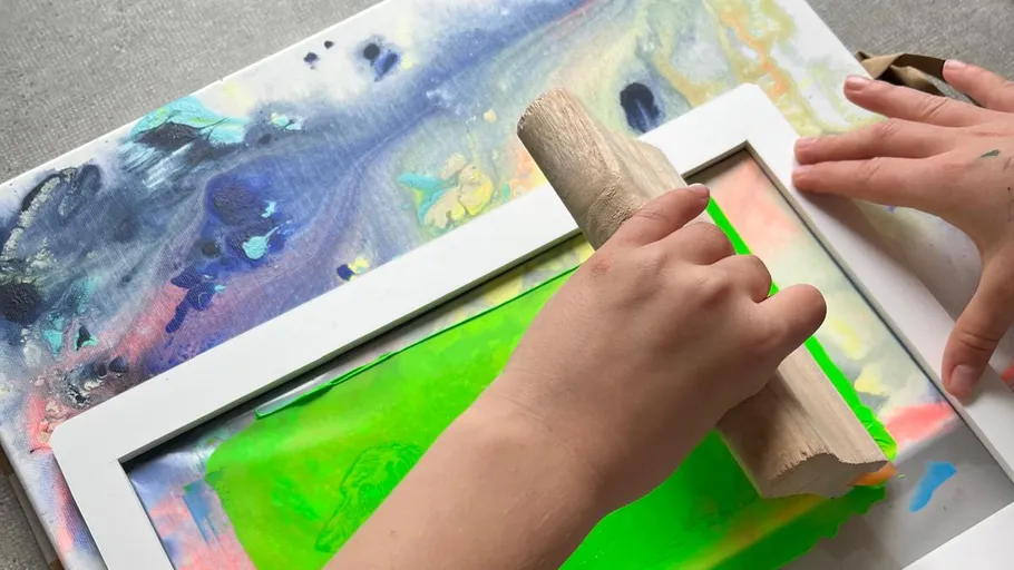 Hands using squeegee for screen printing.