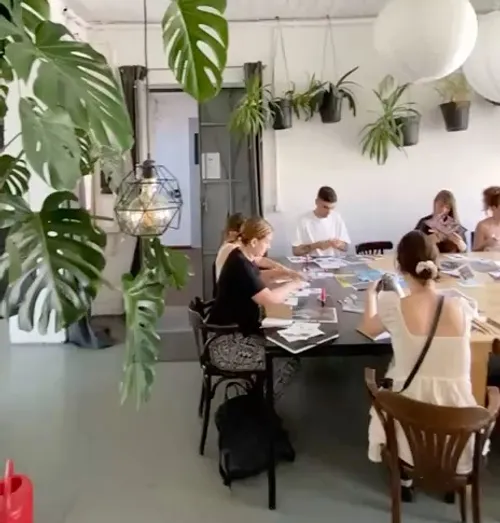 People crafting at a table in a plant-filled room.