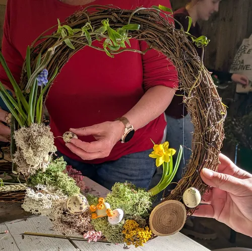 Hands crafting a decorative wreath indoors.