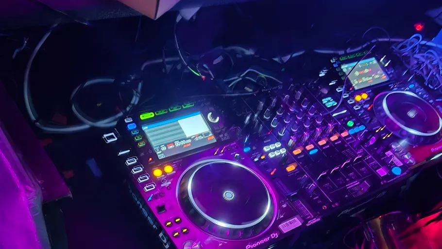 DJ-Ausrüstung mit leuchtenden Steuerungen und Bildschirmen.