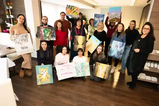 Gruppe hält Gemälde in einem Raum.