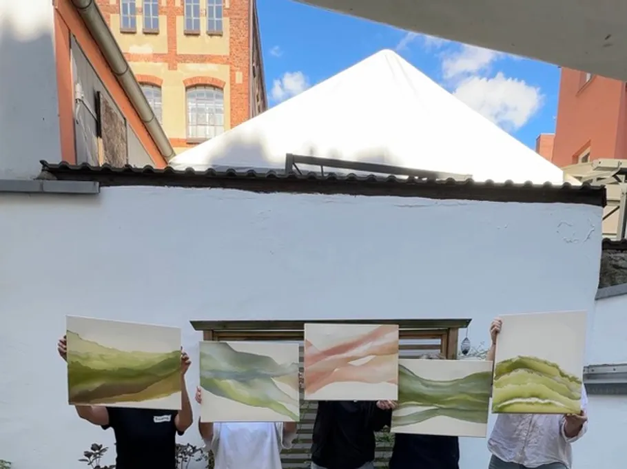 People holding paintings, standing outdoors.